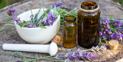 Herbal oil and lavender flowers on a wooden background. Nature.