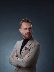 Portrait of a stylish elegant senior businessman with a beard and casual business clothes in photo studio isolated on dark background gesturing with hands
