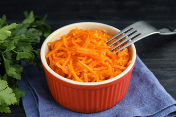 Delicious Korean carrot salad and parsley on black wooden table