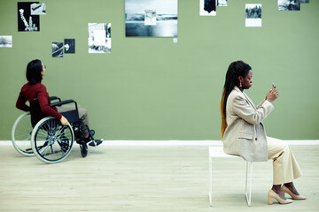 Unrecognizable man with disability and African American woman visiting modern photography...