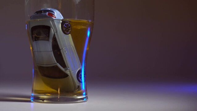 Car is drowning in a glass of alcohol. Social advertising. Concept of drunk driving, car accident. Flashing police lights on the background.