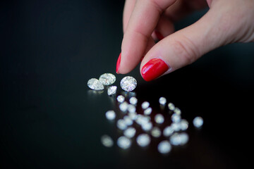 Diamonds are placed on a black table , Diamonds , A woman holding diamonds, a woman's hand touching a diamond , Diamonds on a black background