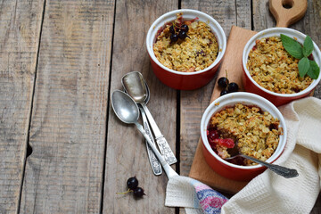 Fruits casserole or crumble with apples and berries in brown cup ramekin. Copy space. Photographing with natural light.