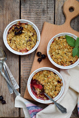 Fruits casserole or crumble with apples and berries in brown cup ramekin. Copy space. Photographing with natural light.