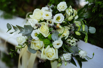 Beautiful wedding bouquet. Roses in pastel colors. Bridal flowers. Golden rings for couple.