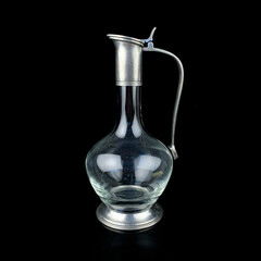 antique glass decanter with a metal figured neck. retro decanter for alcohol on a black isolated background