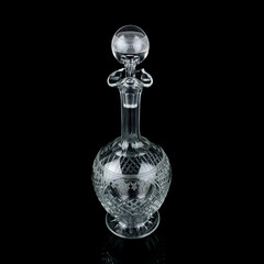 antique glass decanter with geometric pattern. retro decanter for alcohol on a black isolated...
