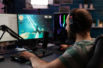 Person streaming video games online with live chat. Player using headphones and microphone on computer, to play gameplay on live stream. Man broadcasting game with equipment at desk.