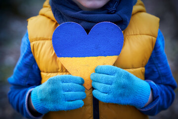 Picture of a child with a lot of love and peaceful message holding heart