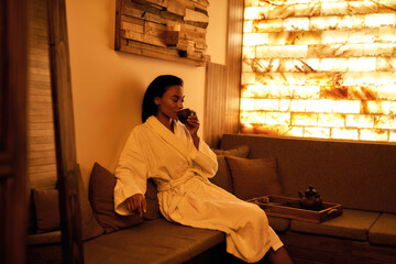 Young black girl drinking tea in spa salon