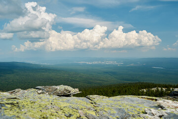 white voluminous clouds over a green valley, stones in the foreground