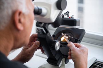A gemologist looks at a diamond through a microscope, gemstones appraisal. gemologist holding a brilliant cut ruby and placing on the precision scale, Instruments gemologist, Craftsman appraising