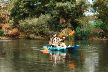 Fototapeta na wymiar Happy adult caucasian man kayaking at the river. Copy space. The concept of the World Tourism Day