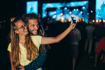 Couple taking selfie with a smartphone on a music festival