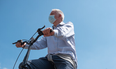 Man riding his bike in a city while wearing a covid coronavirus mask