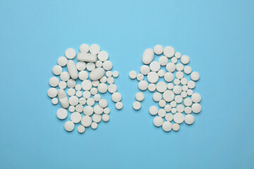 White pills in shape of kidneys on light blue background, flat lay
