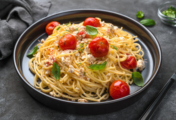 Spaghetti with fett cheese, cherry tomatoes and herbs close-up.