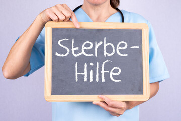 Ärztin zeigt auf eine Tafel auf der Sterbehilfe steht