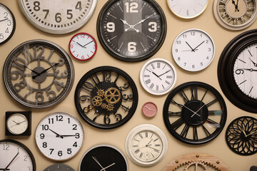 Collection of stylish clocks on beige wall