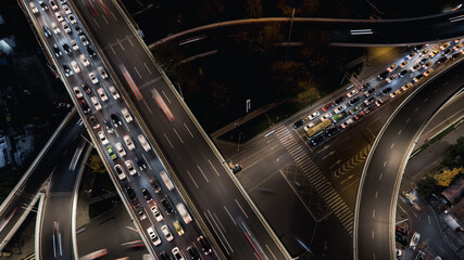 Aerial top down of multilevel elevated road huge traffic junction in modern metropolis city. Night long exposure motion blur of vehicles. Modern development of infrastructure and motorways in China.