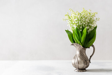 Lovely lily may flowers in a vintage vase on white background with copy space. Floral spring background. Greeting card