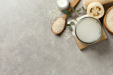 Flat lay composition with natural rice water on light grey table. Space for text
