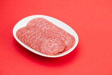 fresh cut salami on small white plate on red