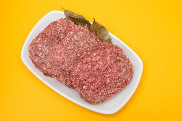 fresh raw minced meat on white dish with bay leaf