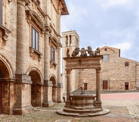 Obraz premium The medieval stone well (Pozzo dei Grifi e dei Leoni) with griffins and lions on the central Piazza Grande in Montepulciano, Tuscany, Italy