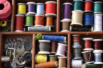 View into a workbasket with spools of sewing thread in many colours.