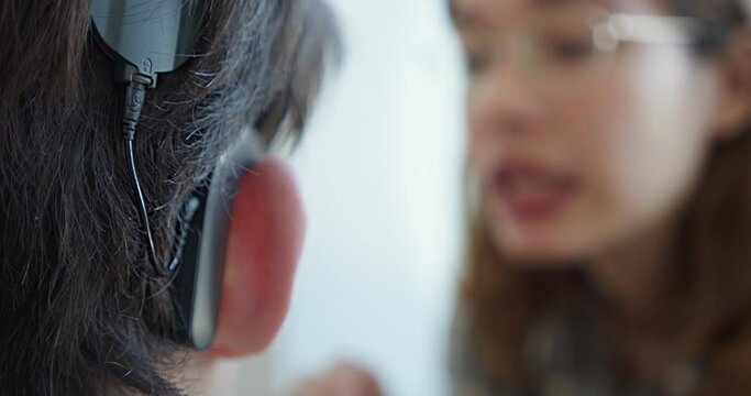 a woman speech therapist, deals with a person with hearing problems, articulates words. close-up hearing aid