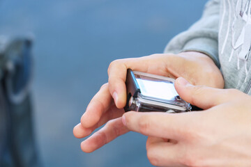 A man holds in his hands and looks through the footage on an action camera