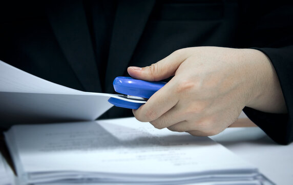 Employees in the company use a blue stapler to staple documents in the office. Office equipment for collecting documents
