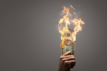 Burning US Dollar bill held by a hand