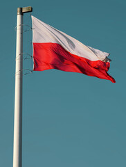 Polish flag waving in the sky. Waving national flag of Poland on a flagpole, national colors of Poland.