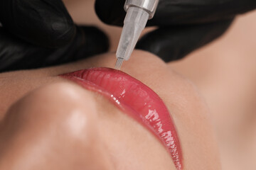 Young woman during procedure of permanent lip makeup in beauty salon, closeup