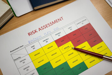 A pen is placed on paper with marked on medium level of the project risk assessment evaluation...