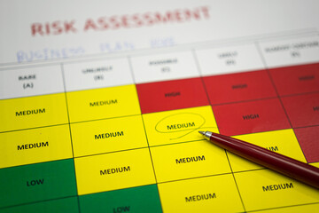 A pen is placed on paper with marked on medium level of the project risk assessment evaluation form. Business and finance concept photo. Selective focus. - obrazy, fototapety, plakaty
