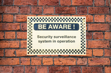 BE AWARE - security sign on brick wall background