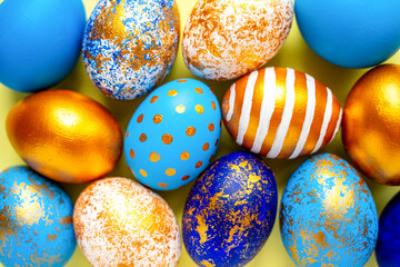 colored golden, blue, light blue Easter eggs on a yellow background for Easter