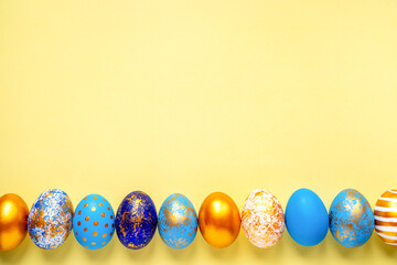 colored golden, blue, light blue Easter eggs on a yellow background for Easter