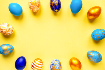 colored golden, blue, light blue Easter eggs on a yellow background for Easter