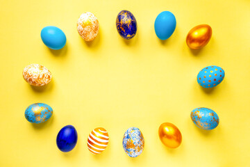 Fototapeta na wymiar colored golden, blue, light blue Easter eggs on a yellow background for Easter