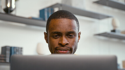 Young serious man receiving news chatting on the internet using laptop