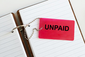 UNPAID inscription on a red card on a chain on a notebook on a table, a business concept