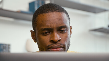 Young african freelancer man working on computer at home. Serious man work at home