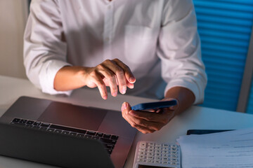 Overwork Concept The office man who sits at his desk holding his smartphone for searching some information