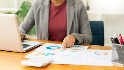 Business analyst concept the data analyst holding and pointing her pen at the document about sale chart