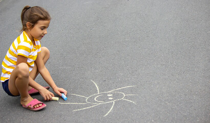 Naklejka premium the child draws with chalk on the pavement, the heart is the sun. Nature.