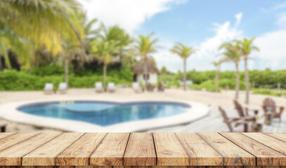 Empty wooden table with swimingpool in the beach on background
